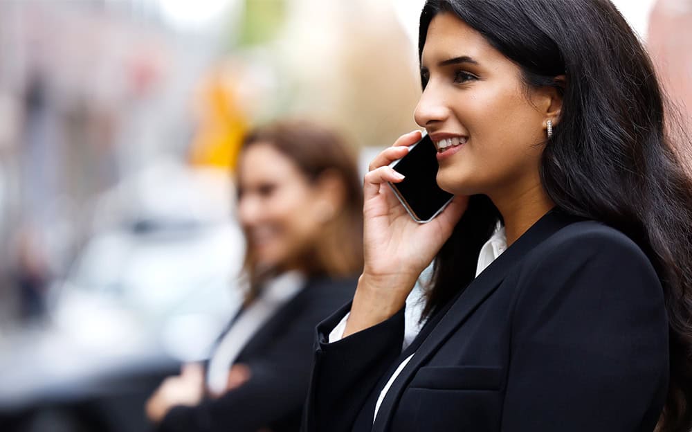 Kvinna i affärskostym som pratar i telefon, perfekt exempel på att boka möte personlig rådgivning.